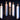 Five lit white ritual candles of varying heights on a dark textured surface.