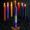Colorful ritual spell candles lit on a bed of dried herbs for spiritual practice.