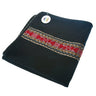 Folded black ritual textile with red and gold ethnic woven pattern.