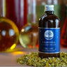 Organic Calendula infused oil in a dark glass bottle surrounded by dried chamomile flowers.