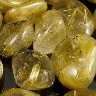 Polished golden rutile quartz tumblestones with visible metallic inclusions