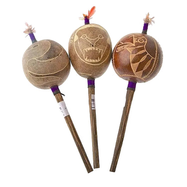 Three handcrafted shamanic rattles with carved animal designs and wooden handles.