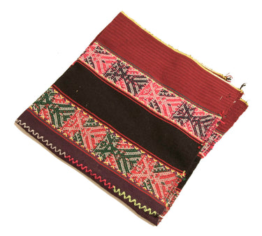 A rectangular zippered pouch or clutch with horizontal woven textile bands, featuring red, black, green, and pink geometric patterns on a white background.