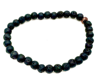 A beaded stretch bracelet made of dark, porous lava stone beads with a small rose gold accent bead near the top right.