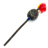 A handcrafted wooden toy mace or staff with a carved black oval head featuring geometric gold patterns, a long dark brown wooden handle, and a vibrant red and yellow feather tassel, shown on a plain white background.