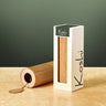 A Koshi rice paper reed roller and its white packaging box on a beige stone surface against a dark green background.