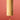 A bamboo cylindrical wind chime with a small wooden striker hanging below, suspended by a black cord against a solid red background.