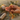 Hands holding a wooden mala prayer bead necklace with a tassel, surrounded by dried herbs.