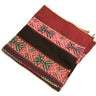 A rectangular zippered pouch or clutch with horizontal woven textile bands, featuring red, black, green, and pink geometric patterns on a white background.