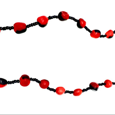 A beaded necklace featuring alternating large red and black marbled beads with smaller black seed beads.