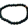 A beaded stretch bracelet made of dark, porous lava stone beads with a small rose gold accent bead near the top right.