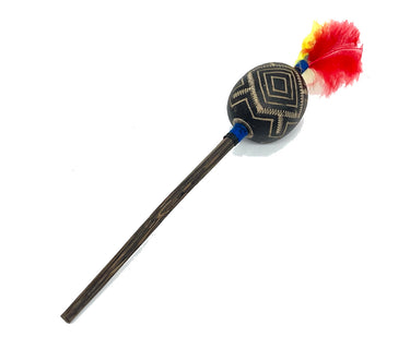 A handcrafted wooden toy mace or staff with a carved black oval head featuring geometric gold patterns, a long dark brown wooden handle, and a vibrant red and yellow feather tassel, shown on a plain white background.