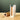 A Koshi rice paper reed roller and its white packaging box on a beige stone surface against a dark green background.