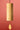 A bamboo cylindrical wind chime with a small wooden striker hanging below, suspended by a black cord against a solid red background.