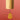 A bamboo wind chime with a cylindrical body and a teardrop-shaped wooden striker hanging from a black cord, set against a solid coral-pink background.