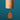 A wooden wind chime with a cylindrical body and a teardrop-shaped hanging striker, shown against a solid teal background. The brand name 'Kaleidoscope' is engraved on the side of the cylinder.