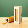 A rectangular cream-colored box with a vertical window displaying a light wood insert, standing next to a matching cylindrical wooden box lying on its side. The cream box has the brand name 'Kosli' written vertically in black.