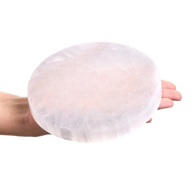 A hand holding a large, round, translucent white crystal sphere against a solid white background.
